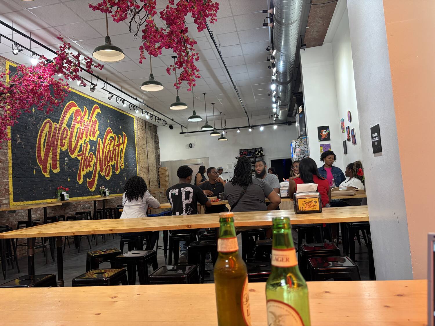 Inside Spinelli's Pizzeria downtown Louisville — the 'We Own the Night!' mural, communal tables, a late-night crowd